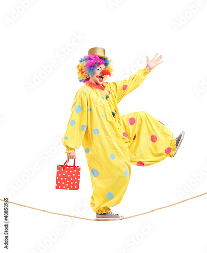 Photo: Full length portrait of a clown holding a bag and walking on a r Full length portrait of a clown holding a bag and walking on a r