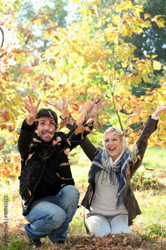 Photo: man and woman throwing leaves man and woman throwing leaves