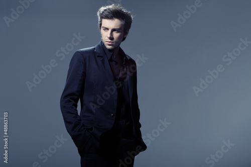 Photo: Portrait of a young business man leaning against the wall Portrait of a young business man leaning against the wall