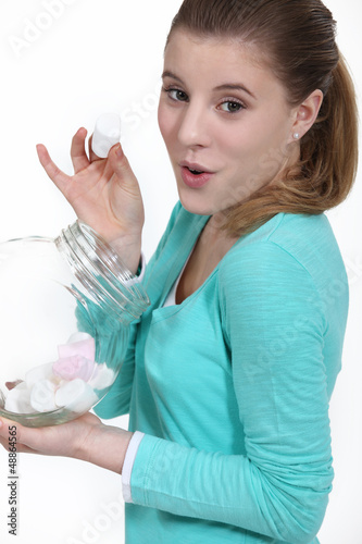 Photo: Cheeky woman eating marshmallow from jar Cheeky woman eating marshmallow from jar