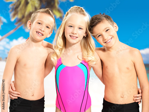 Photo: Portrait of the happy children enjoying at beach Portrait of the happy children enjoying at beach
