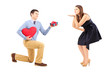 Photo: Man kneeling and giving and present to a woman blowing h Man kneeling and giving and present to a woman blowing h