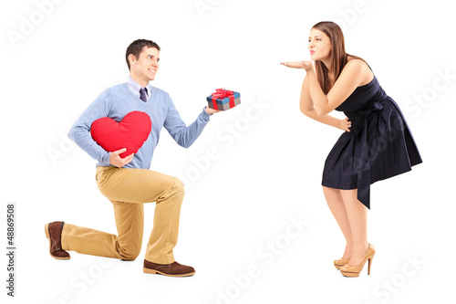 Photo: Man kneeling and giving and present to a woman blowing h Man kneeling and giving and present to a woman blowing h