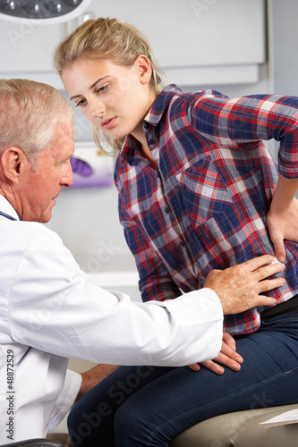 Photo: Teenage Girl Visits Doctor's Office With Back Pain Teenage Girl Visits Doctor's Office With Back Pain