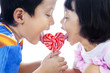 Cute siblings lick lollipop
