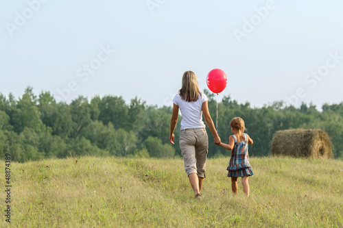Photo: Mother and daughter go from the camera in ibeautiful field Mother and daughter go from the camera in ibeautiful field