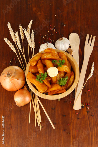 Photo: Appetizing village potatoes in bowl on wooden table close-up Appetizing village potatoes in bowl on wooden table close-up