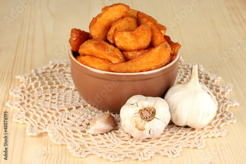 Photo: Appetizing village potatoes in bowl on wooden table close-up Appetizing village potatoes in bowl on wooden table close-up