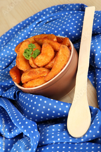 Photo: Appetizing village potatoes in bowl on blue fabric close-up Appetizing village potatoes in bowl on blue fabric close-up