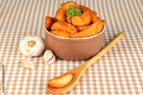 Photo: Appetizing village potatoes in bowl on beige tablecloth Appetizing village potatoes in bowl on beige tablecloth