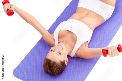 Photo: woman laying on the floor and lifting dumbbells woman laying on the floor and lifting dumbbells