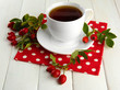 cup of tea with hip roses, on wooden table