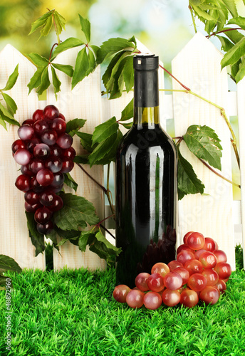 Photo: a bottle of wine on the fence background close-up a bottle of wine on the fence background close-up
