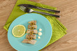 Dish of herring and lemon on plate on wooden table close-up