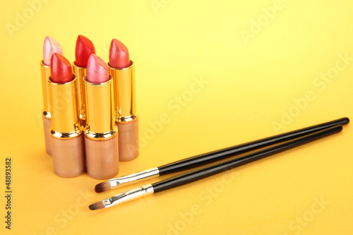 Photo: Lipsticks and brushes on yellow background Lipsticks and brushes on yellow background