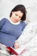 pregnant woman reads the book, lying in a bed