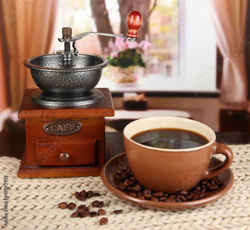 Photo: cup of coffee with scarf and coffee mill on table in room cup of coffee with scarf and coffee mill on table in room