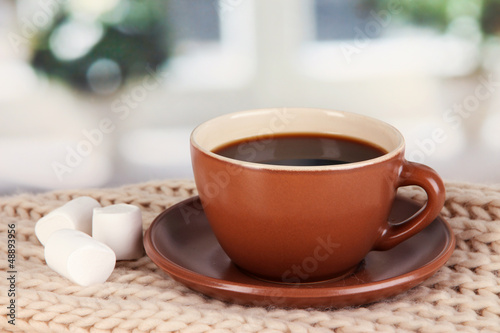 Photo: cup of coffee with scarf on table in room cup of coffee with scarf on table in room