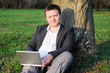 Businessman with laptop working under a tree