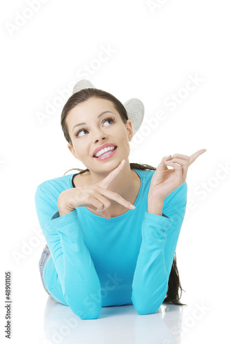 Photo: Woman lying on floor and pointing on copy space Woman lying on floor and pointing on copy space