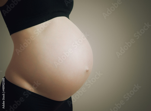 Photo: belly of pregnant woman on dark background belly of pregnant woman on dark background