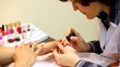 Cosmetician accurately covers nails of client with pink nail