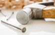hammer and nails on a wood board with sawdust shavings