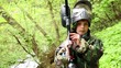 Video: Boy stands with paintball gun at background of green leaves Boy stands with paintball gun at background of green leaves
