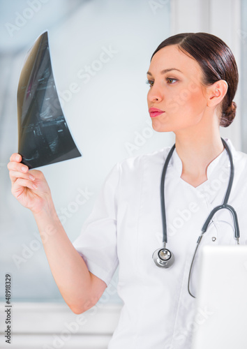 Photo: Portrait of a female doctor holding ultrasound results and using Portrait of a female doctor holding ultrasound results and using