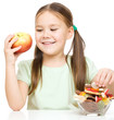Little girl choosing between apples and sweets
