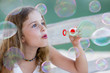 Summer joy - lovely girl blowing soap bubbles