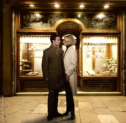 Photo: Elegant couple against bakery shop window Elegant couple against bakery shop window