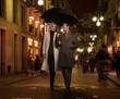 Elegant couple with umbrella outdoors on rainy evening