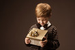 Child holding gift box and looking at present. Vintage style.