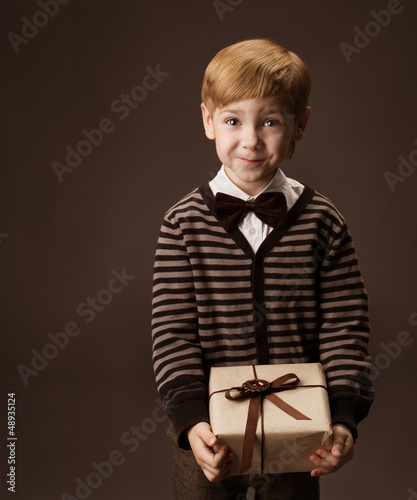 Photo: Child holding gift box. Vintage style. Funny looking Child holding gift box. Vintage style. Funny looking