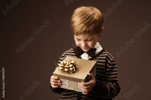 Photo: Child holding gift box and looking at present. Vintage style. Child holding gift box and looking at present. Vintage style.