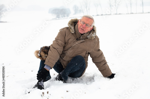 Photo: Senior man with injured leg on snow Senior man with injured leg on snow
