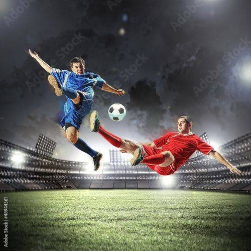 Photo: two football players striking the ball two football players striking the ball