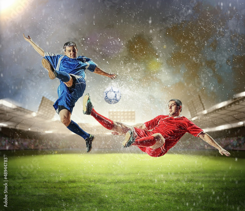 Photo: two football players striking the ball two football players striking the ball