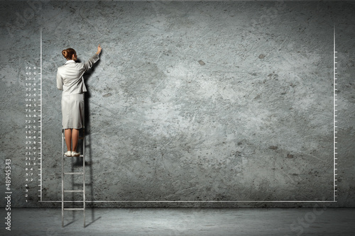 Photo: businesswoman drawing diagrams on wall businesswoman drawing diagrams on wall