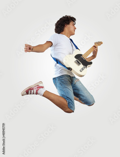 Photo: young man playing on electro guitar and jumping young man playing on electro guitar and jumping