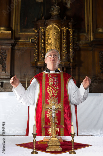 Photo: Priest praying during mass Priest praying during mass