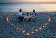 A young lovers couple share a romantic dinner with candles heart