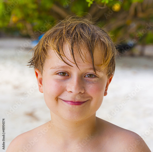 Photo: happy boy with wet hair at the beach smiles happy boy with wet hair at the beach smiles