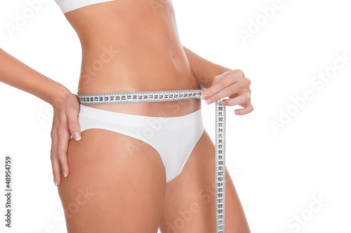 Photo: fit young woman measuring her waistline, white background fit young woman measuring her waistline, white background