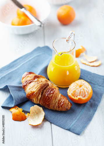 Photo: Croissant and mandarin juice on a blue napkin Croissant and mandarin juice on a blue napkin