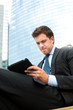 Businessman using a tablet on a bench in the city