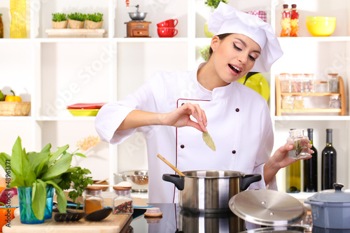 Photo: Young woman chef cooking in kitchen Young woman chef cooking in kitchen