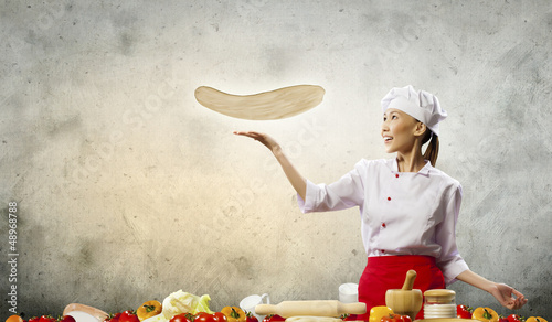 Photo: Asian female cook making pizza Asian female cook making pizza