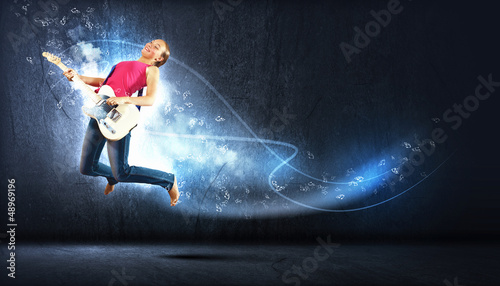 Photo: young woman playing on electro guitar and jumping young woman playing on electro guitar and jumping